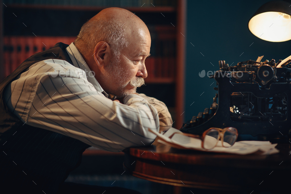 Elderly writer thinks at vintage typewriter - Stock Photo - Images