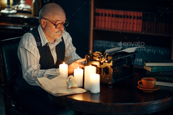 Adult writer works on typewriter with candle light - Stock Photo - Images