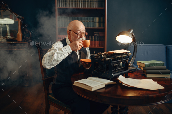 Elderly writer drinks coffee at vintage typewriter