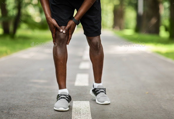 Closeup of black sportsman rubbing his sore knee