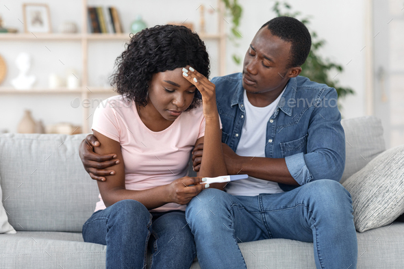 African man hugging his upset wife, having negative pregnancy test