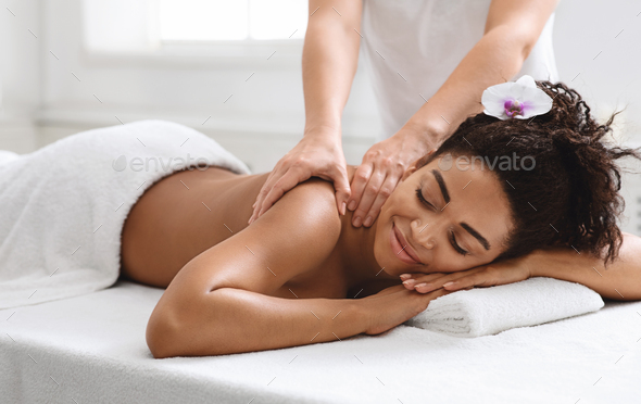 Relaxed black girl enjoying full body massage at new spa