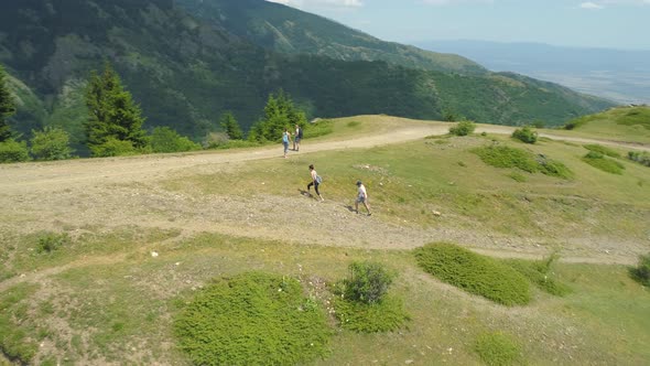 Drone View of Group of Hikers Reaching the Top of a Hill with Forested Mountains Around alt