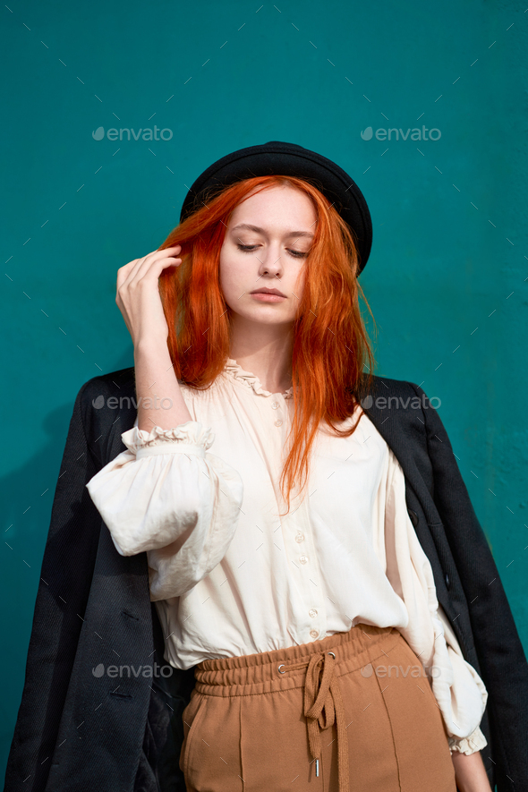 Redhead woman is resting against bright green wall - Stock Photo - Images