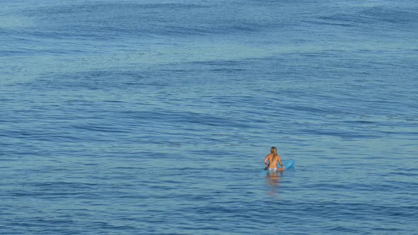 A young woman surfing in a bikini on a longboard surfboard. alt