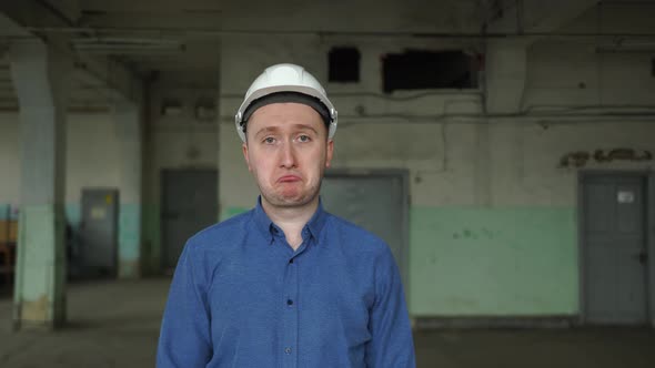An Engineer in a Helmet Looks at the Camera is Very Sad Upset Failure at Work