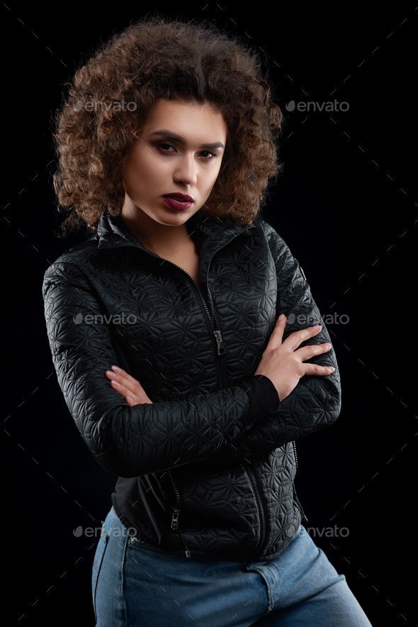 Confident curly girl wearing black jacket and blue jeans - Stock Photo - Images