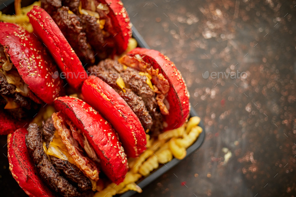 Set of four homemade giant double becon cheese burgers. Served with french fries on wooden board - Stock Photo - Images