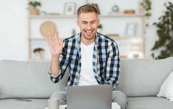 Happy guy using computer for video call and waving