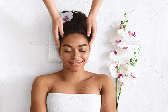 Top view of joyful black woman getting head massage