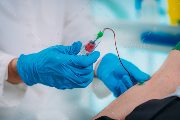 Medical worker with PPE taking blood sample from patient in a hospital ...