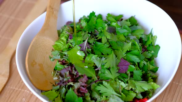 Woman Cook Pours Olive Oil on Vegan Salad alt