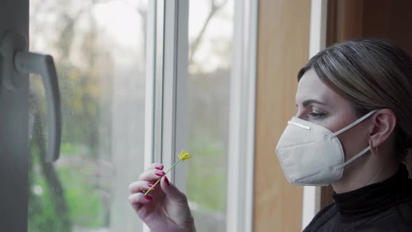 Woman in protective mask sniffing a flower