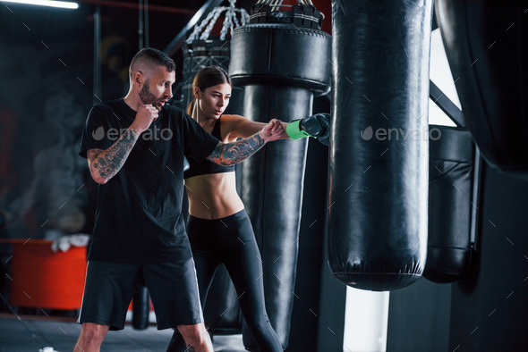 Young tattooed boxing coach teaches young woman in the gym - Stock Photo - Images