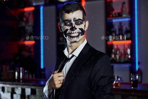 Portrait of man that is on the thematic halloween party in scary skeleton makeup and costume