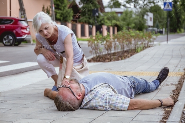 Helpful passerby checks the vital functions of the person who fainted on the street