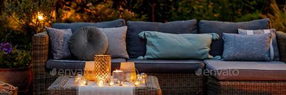 Warm summer night in the garden with trendy furniture, lights, lanterns and candles