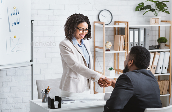 Black hiring manager shaking hands with successful vacancy candidate after work  interview at office Stock Photo by Prostock-studio