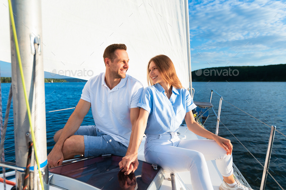 Cheerful Spouses Holding Hands Sitting On Yacht Deck