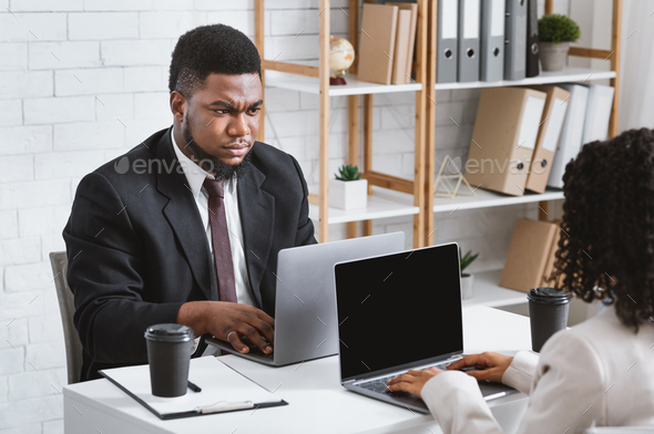 Workplace conflict. Displeased African American guy having disagreement with his female colleague at