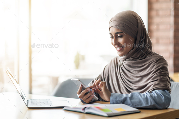 Arab woman freelancer working at cafe, chatting with clients