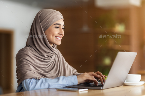 Happy arab woman chatting with clients on laptop