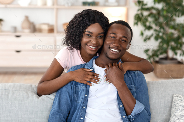 Cheerful african woman hugging her husband from behind