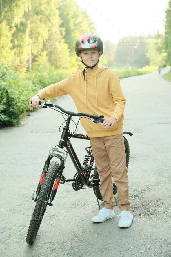Happy youngster in yellow hoodie, beige pants, white sneakers and helmet