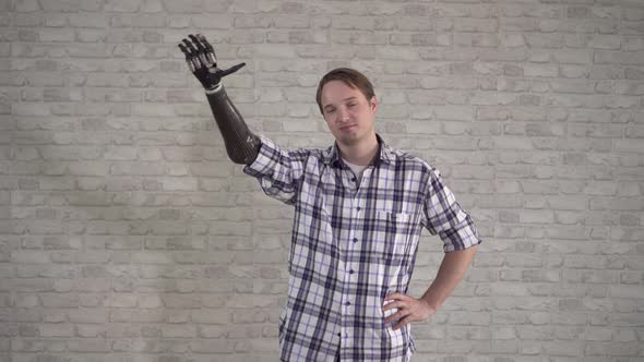 Positive Young Man Waves a Cyber Prosthetic Hand alt