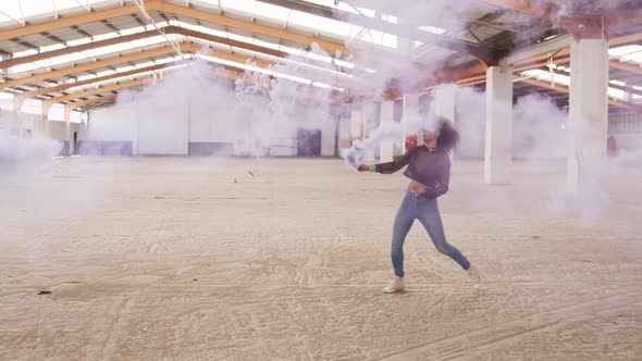 Female dancer in an empty warehouse holding smoke grenade alt