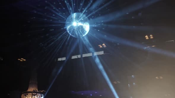 Mirror Disco Ball Spinning and Reflecting Blue Rays of Light in a Nightclub