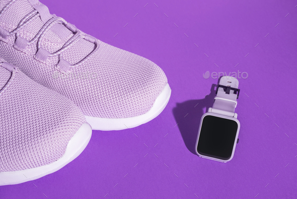 New purple sneakers and smart watch on colorful background