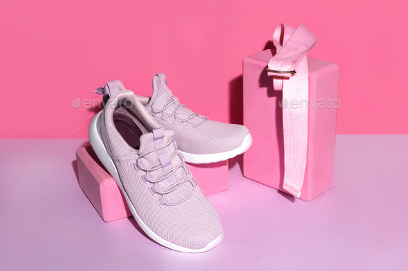 New purple sneakers, pink yogs blocks and strap on colorful background with copy space.