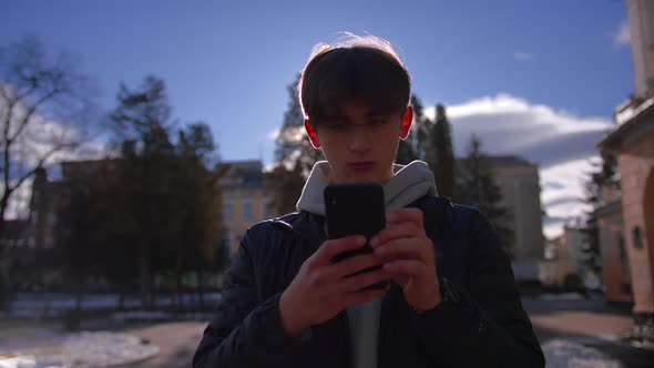 Young Man Texting on Cell Phone Looking Around