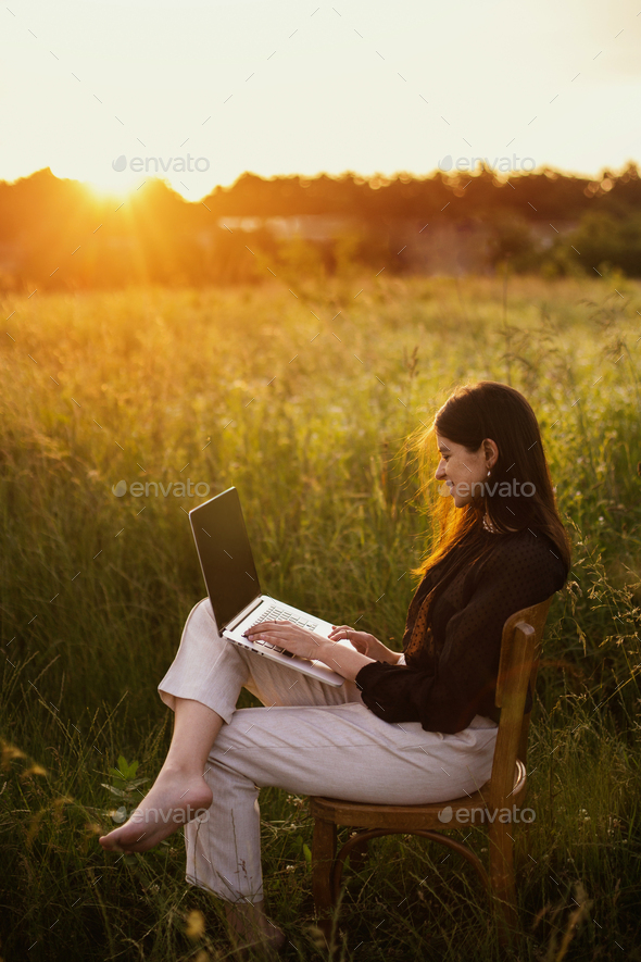 Fashionable elegant girl working on laptop and sitting on rustic chair