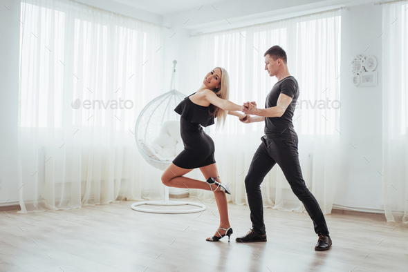 Young couple dancing latin music: Bachata, merengue, salsa. Two elegance pose on white room