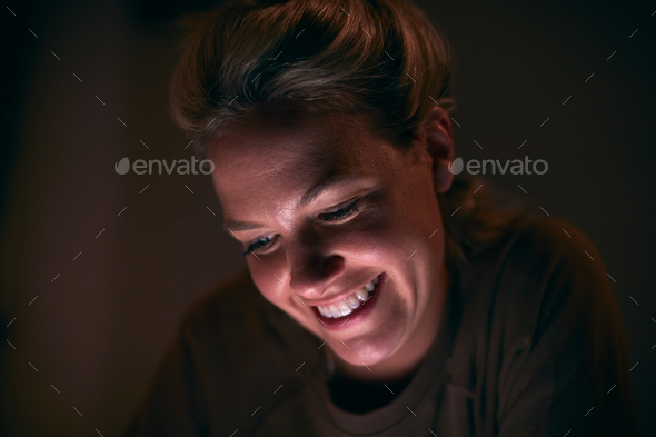 Smiling Woman With Face Illuminated By Digital Tablet Screen At Night