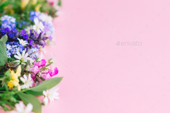 Colorful spring wildflowers border on pink paper background