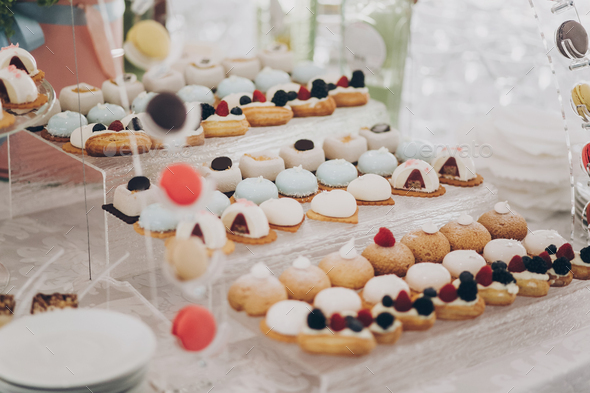 Delicious creamy desserts with fruits, macarons, cakes and cookies on table at wedding reception