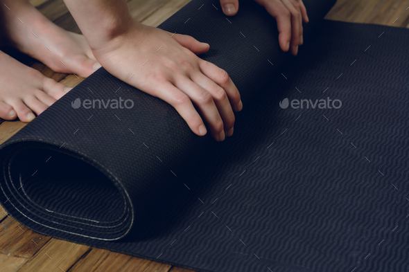 Close-up of young woman rolling her fitness mat