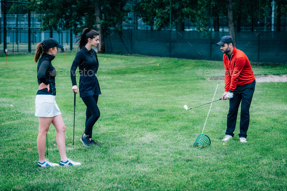 Golf lesson. Golf instructor showing swing technique to young women