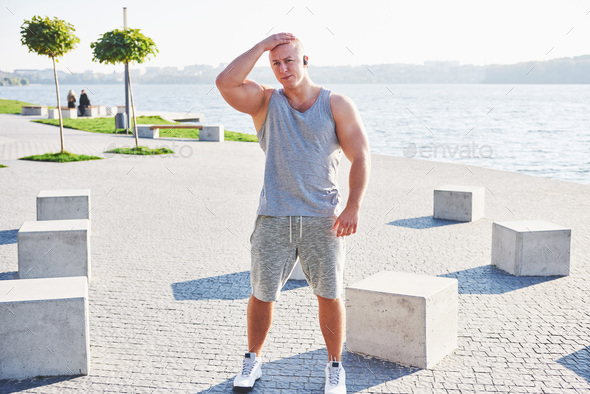 Young male jogger athlete training and doing workout outdoors in city