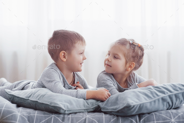 Boy and girl play in matching pajamas. Sleepwear and bedding for child and baby