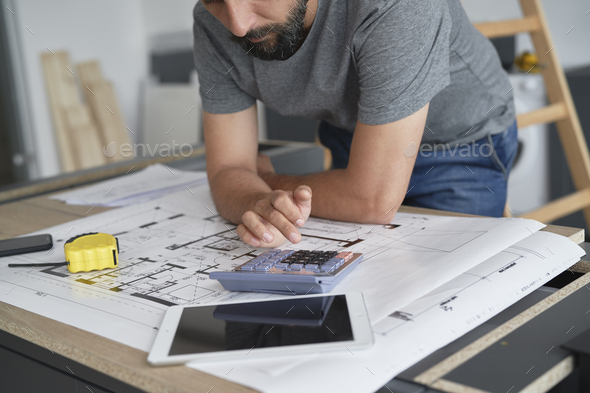 Carpenter calculating something on the calculator - Stock Photo - Images
