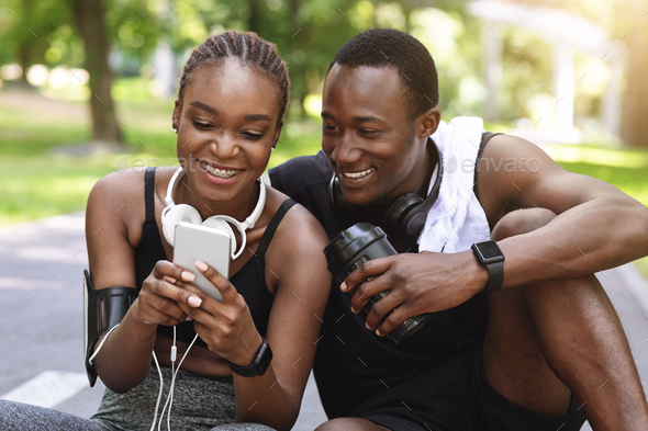 Fit Black Couple Using Smartphone After Training Outdoors, Checking Physical Activity Measurements