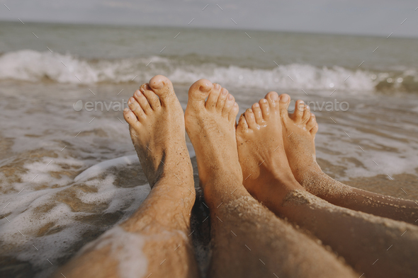 Couple wet feet in sand close up on sunny beach with waves