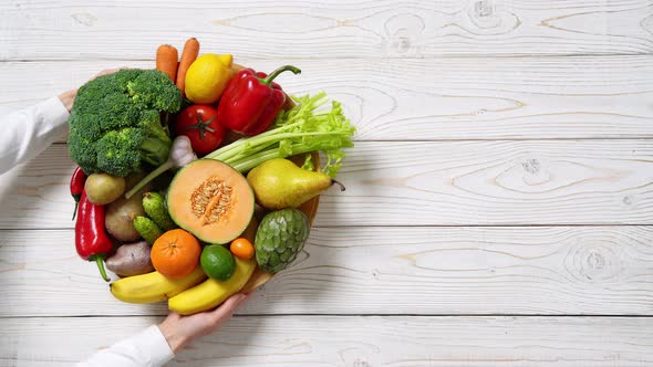 Plate with vegetables and fruits on wooden table. Healthy food, top view.