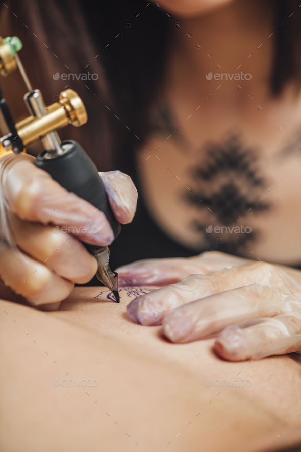 Hand of Tattooist in Rubber Gloves Drawing a Tattoo with Electric Tattoo Gun Close-up