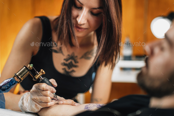 Professional Female Tattooist Working in a Tattoo Studio