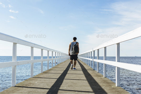 Rear view of young man walking on pier